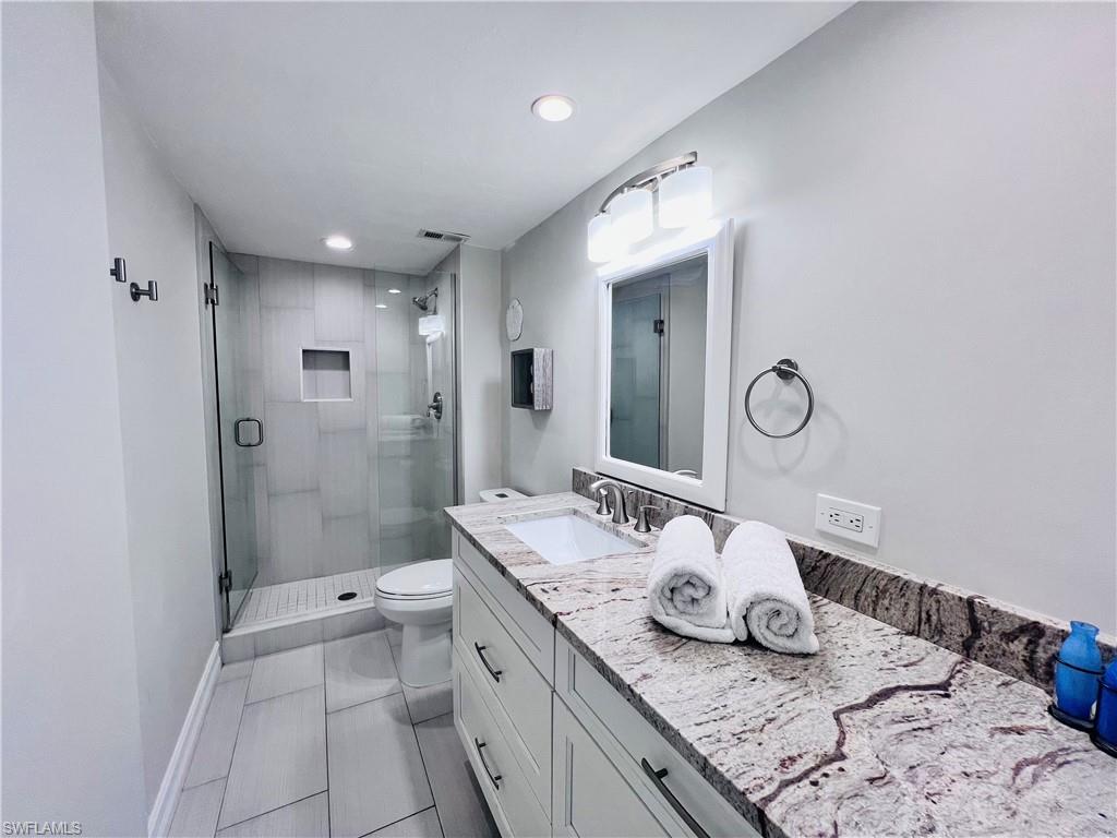 5 Bluebill Avenue, Unit 3031 Naples, FL 34108 - Photo 18 of 24 a bathroom with a granite countertop sink a toilet and shower