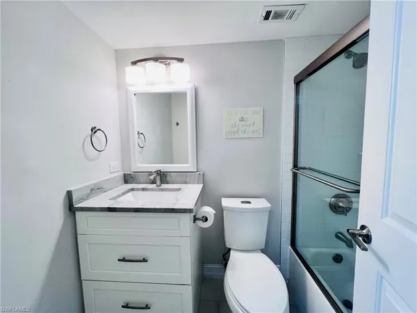 a bathroom with a granite countertop toilet sink and mirror