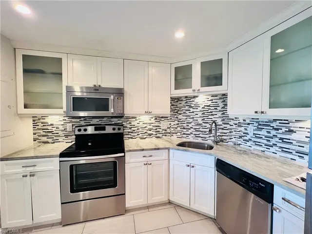 a kitchen with white cabinets and appliances
