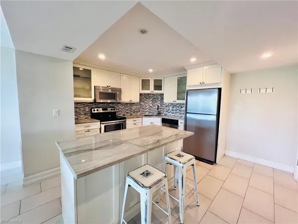 a kitchen with stainless steel appliances granite countertop a refrigerator and a stove top oven