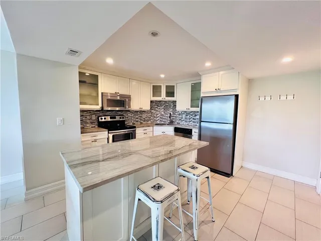 a kitchen with stainless steel appliances granite countertop a refrigerator and a stove top oven