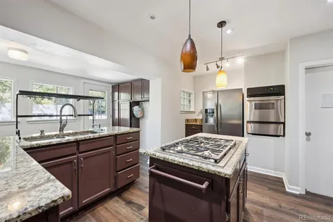 a kitchen with stainless steel appliances granite countertop a sink a stove and a refrigerator