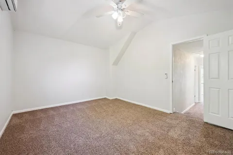 an empty room with chandelier fan and closet area