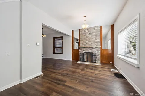 an empty room with wooden floor fireplace and windows