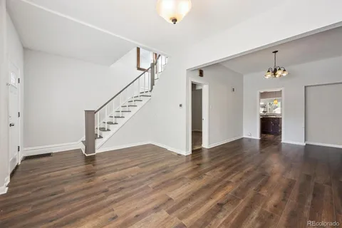 a view of an empty room with wooden floor and stairs