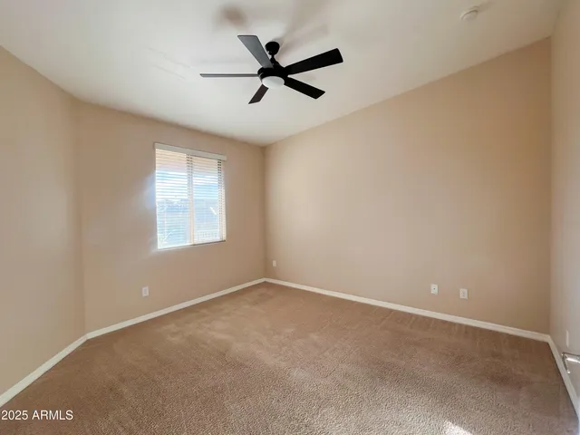 an empty room with ceiling fan and windows