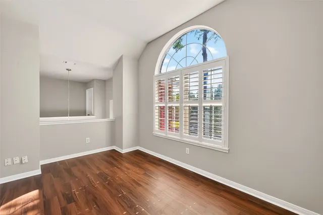 a view of empty room with wooden floor and windows