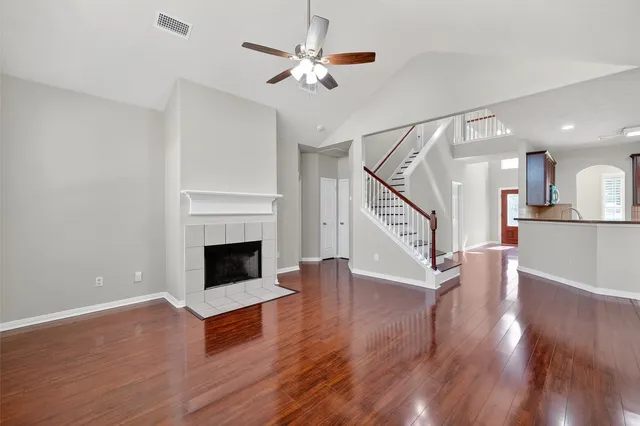 a view of an empty room with wooden floor fireplace and a window