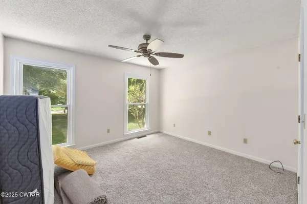 an empty room with windows and fan
