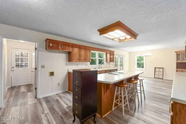 a kitchen with stainless steel appliances granite countertop a stove top oven a refrigerator a dining table and chairs with wooden floor