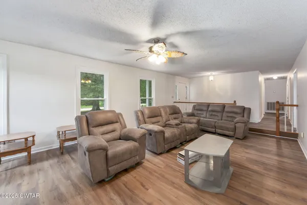 a living room with furniture a ceiling fan a lamp and a window