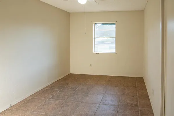 an empty room with wooden floor ceiling fan and windows
