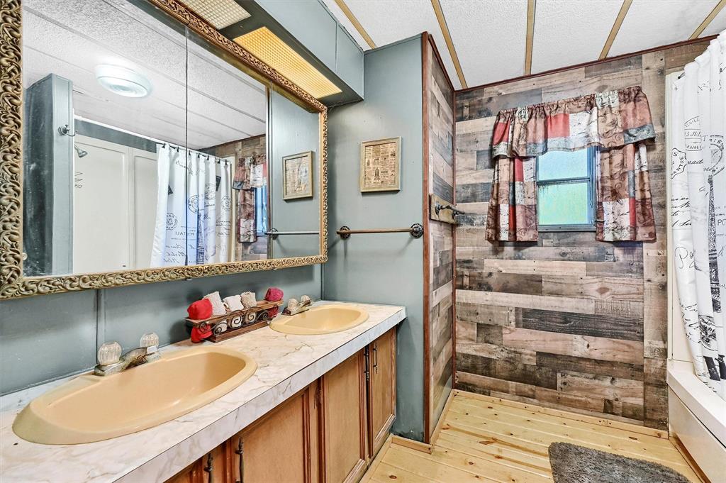 36 Atlantic Street Pottsboro, TX 75076 - Photo 13 of 21 Bathroom featuring wooden walls, curtained shower, wood-type flooring, double vanity, and a textured ceiling