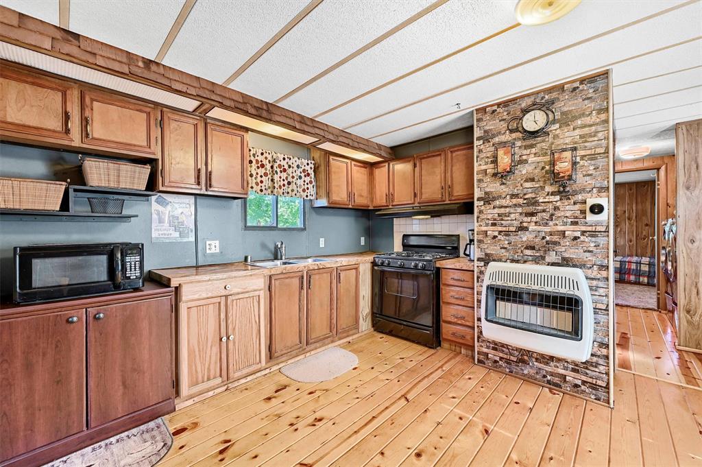 36 Atlantic Street Pottsboro, TX 75076 - Photo 2 of 21 Kitchen with black appliances, heating unit, a sink, light countertops, and light wood finished floors