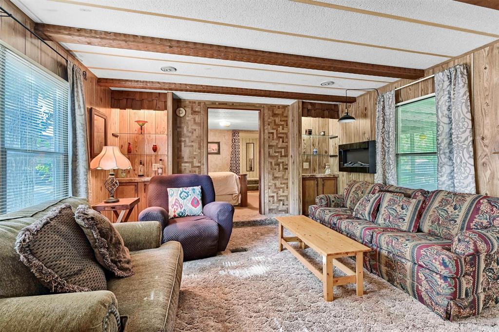 36 Atlantic Street Pottsboro, TX 75076 - Photo 4 of 21 Carpeted living area with plenty of natural light, wood walls, beamed ceiling, and a textured ceiling
