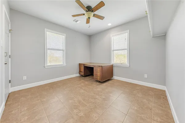 an empty room with windows and ceiling fan