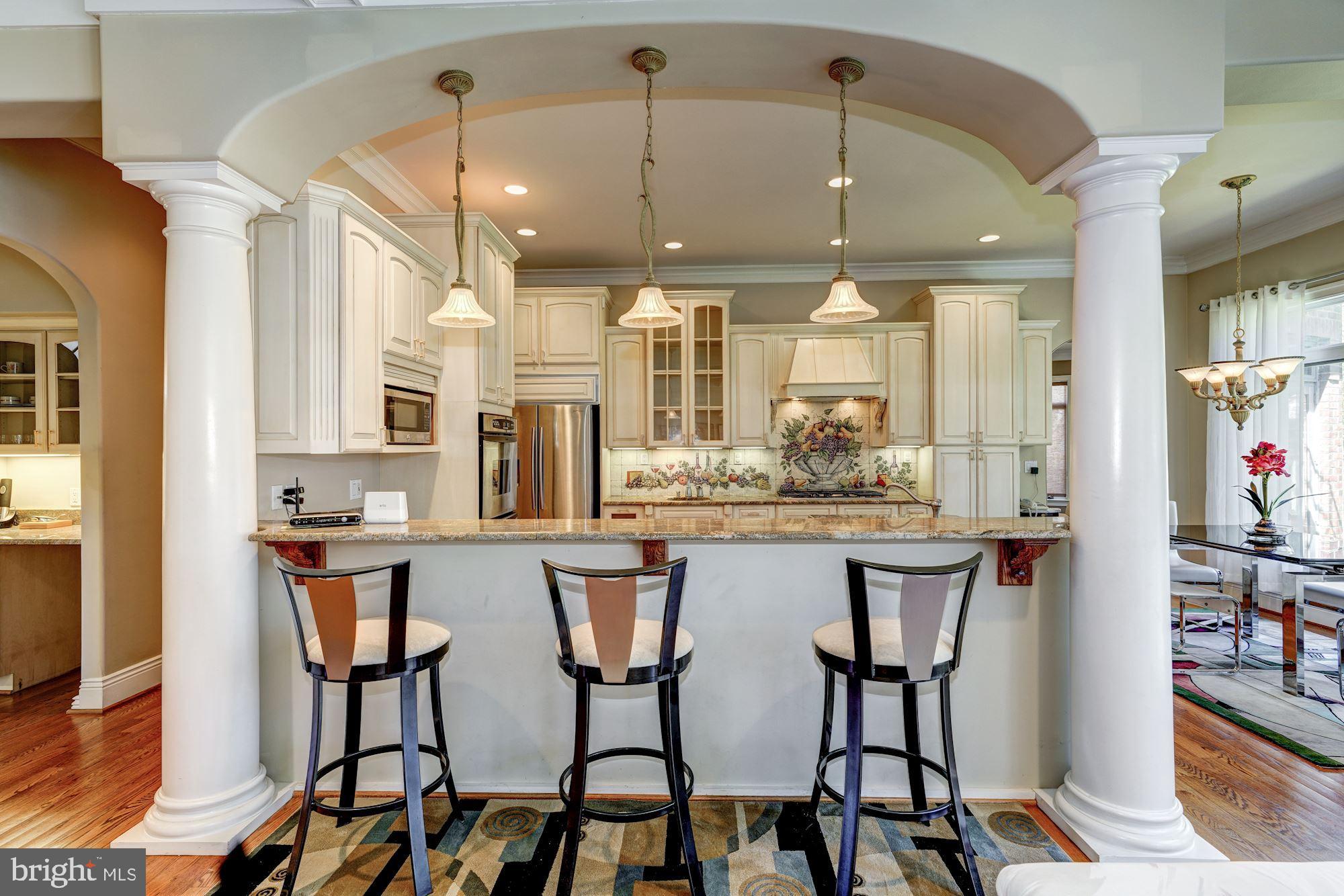 3809 Jones Bridge Road Chevy Chase, MD 20815 - Photo 20 of 70 a kitchen with stainless steel appliances kitchen island granite countertop a dining table chairs and white cabinets