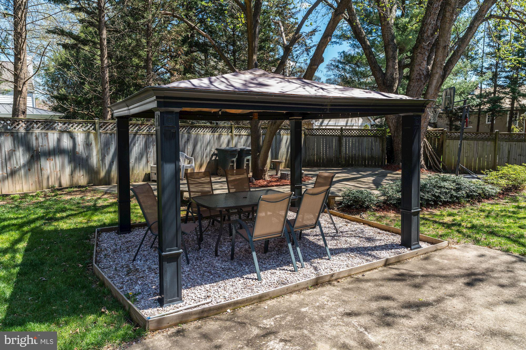3809 Jones Bridge Road Chevy Chase, MD 20815 - Photo 66 of 70 a view of a patio with table and chairs under an umbrella with large trees