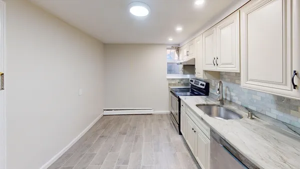 a kitchen with granite countertop a sink a stove and cabinets