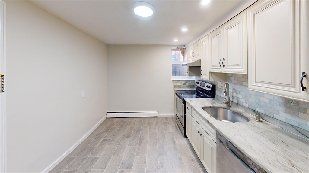 51 Colborne Road, Unit B2 Boston, MA 02135 - Photo 2 of 7 a kitchen with granite countertop a sink a stove and cabinets