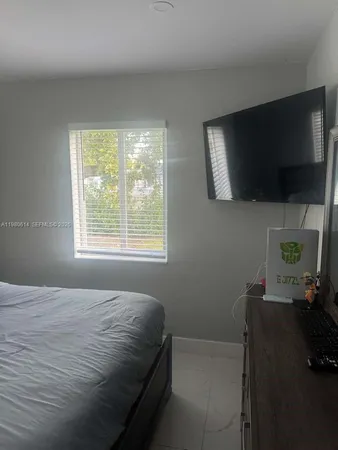 a bedroom with a bed a flat screen tv and guitar