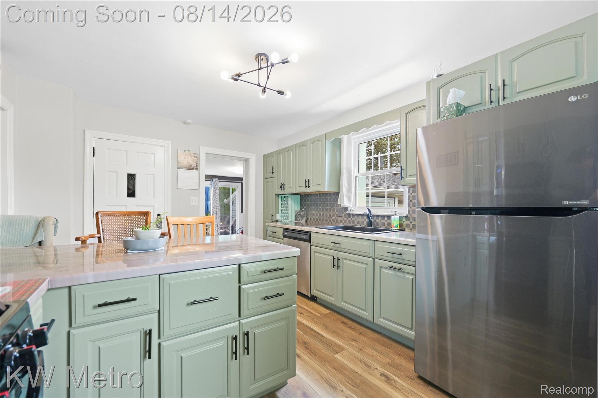 201 South Maple Leaf Road Lapeer, MI 48446 - Photo 5 of 70 Kitchen featuring wood-finish flooring, light-toned cabinetry with dark hardware, stainless steel appliances, and a patterned tile backsplash
