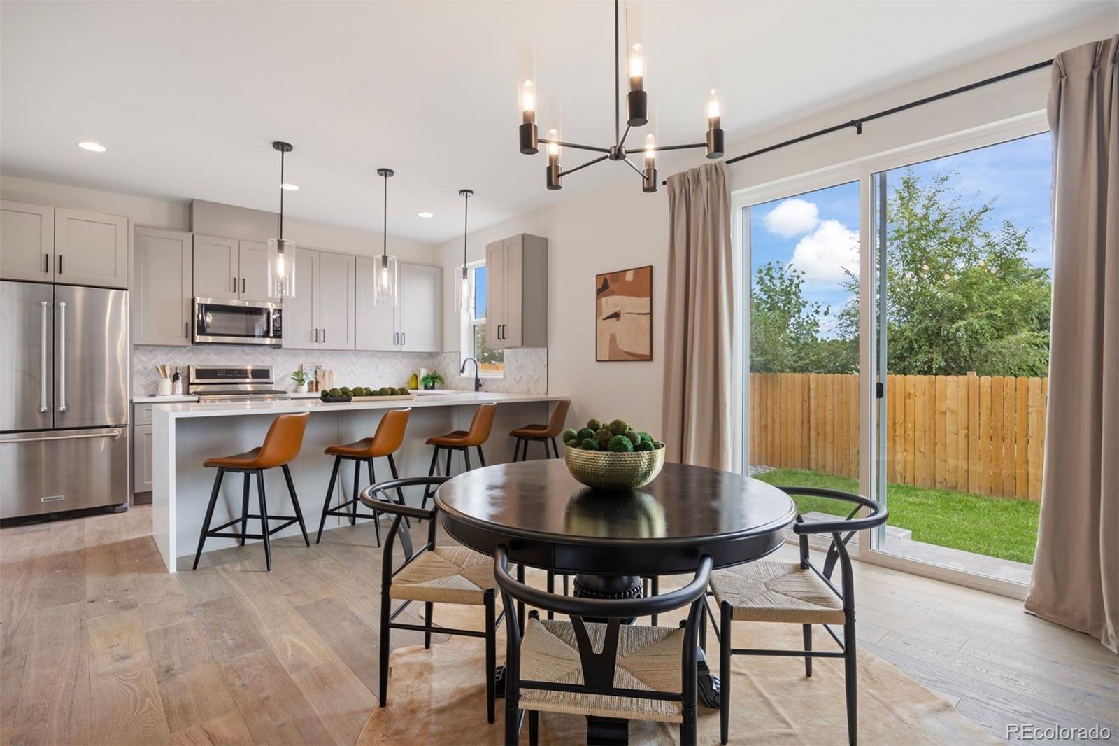 4026 Upham Street Wheat Ridge, CO 80033 - Photo 17 of 50 a kitchen with stainless steel appliances a dining table chairs and couches with wooden floor