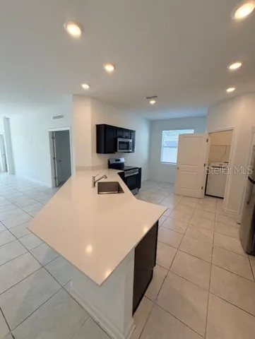 a large white kitchen with a sink a counter top space and stainless steel appliances