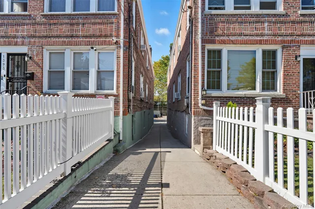 a view of a backyard with large trees and wooden fence