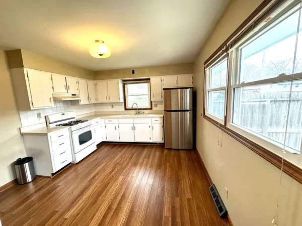 a large kitchen with cabinets wooden floor and stainless steel appliances