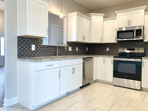 a kitchen with granite countertop white cabinets stainless steel appliances and a sink