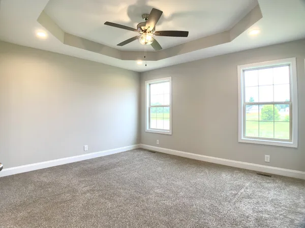 an empty room with windows and fan
