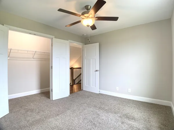 an empty room with closet and a ceiling fan