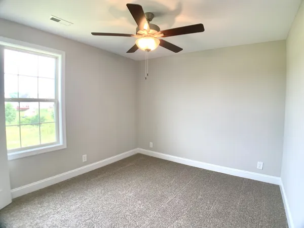 an empty room with a window and a fan