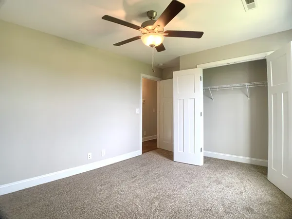 an empty room with closet and a ceiling fan