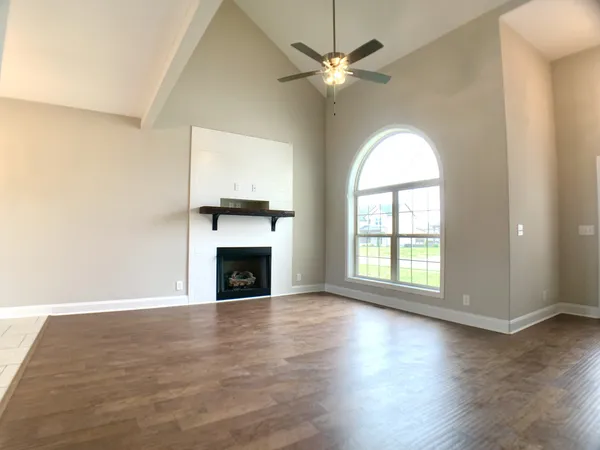 an empty room with wooden floor fireplace and windows