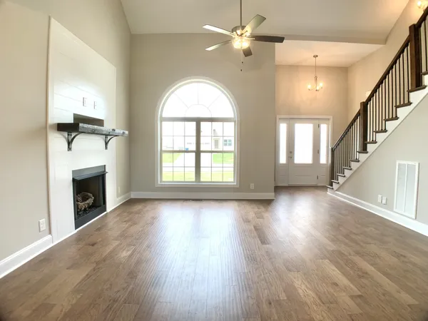 an empty room with wooden floor fireplace and windows