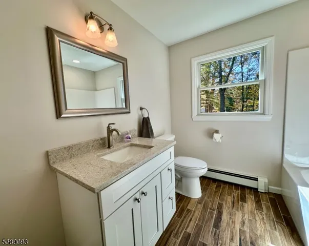 a bathroom with a granite countertop toilet a sink and a mirror