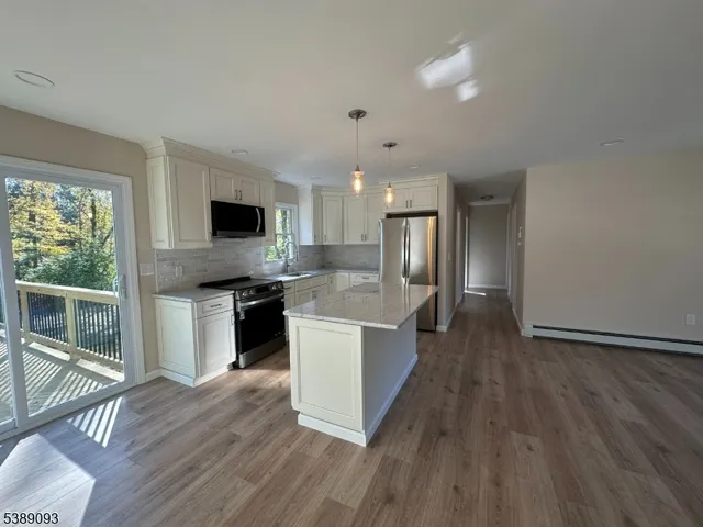 a large kitchen with a center island wooden floor stainless steel appliances and windows