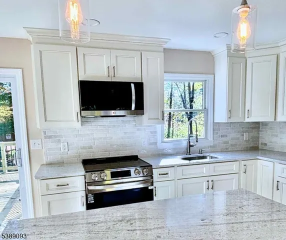 a kitchen with granite countertop a stove a sink and a microwave