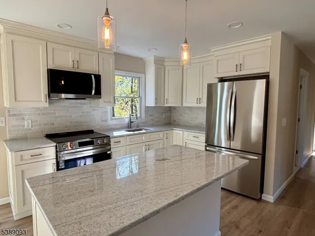 a kitchen with granite countertop a refrigerator a oven a sink a stove and cabinets