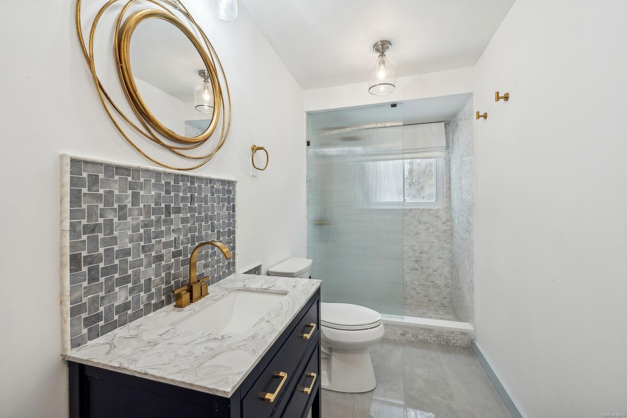 8 Big Reed Path Montauk, NY 11954 - Photo 10 of 39 a bathroom with a granite countertop toilet a sink and a mirror