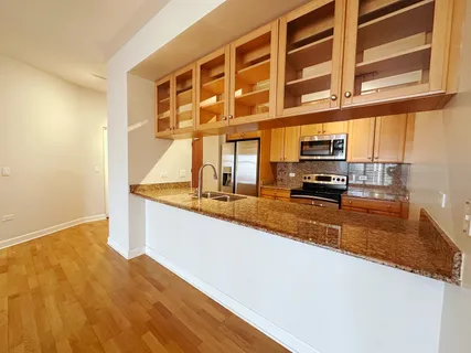 a view of a kitchen with stainless steel appliances granite countertop a sink and cabinets
