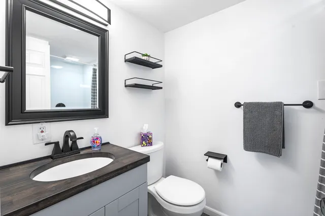 a bathroom with a granite countertop sink vanity mirror and toilet