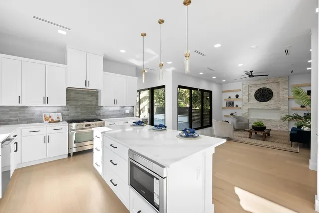 a large white kitchen with a stove a sink a refrigerator and a fireplace