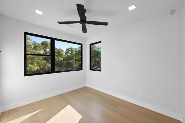 a view of empty room with wooden floor and fan