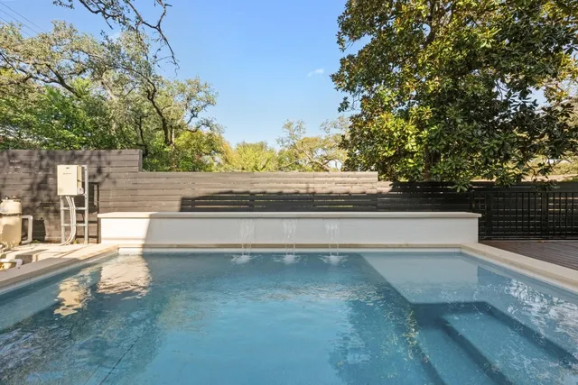 a view of backyard with swimming pool and trees