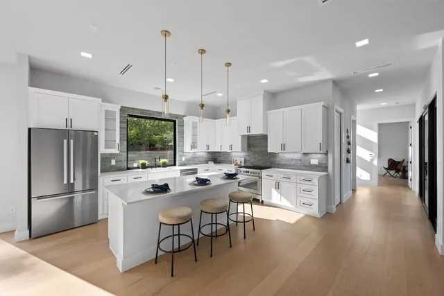 a large kitchen with kitchen island a large counter top stainless steel appliances and cabinets