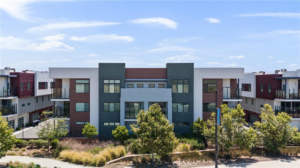 303 Lodestar Tustin, CA 92782 - Photo 32 of 37 a front view of multi story residential apartment building with yard and retail shops