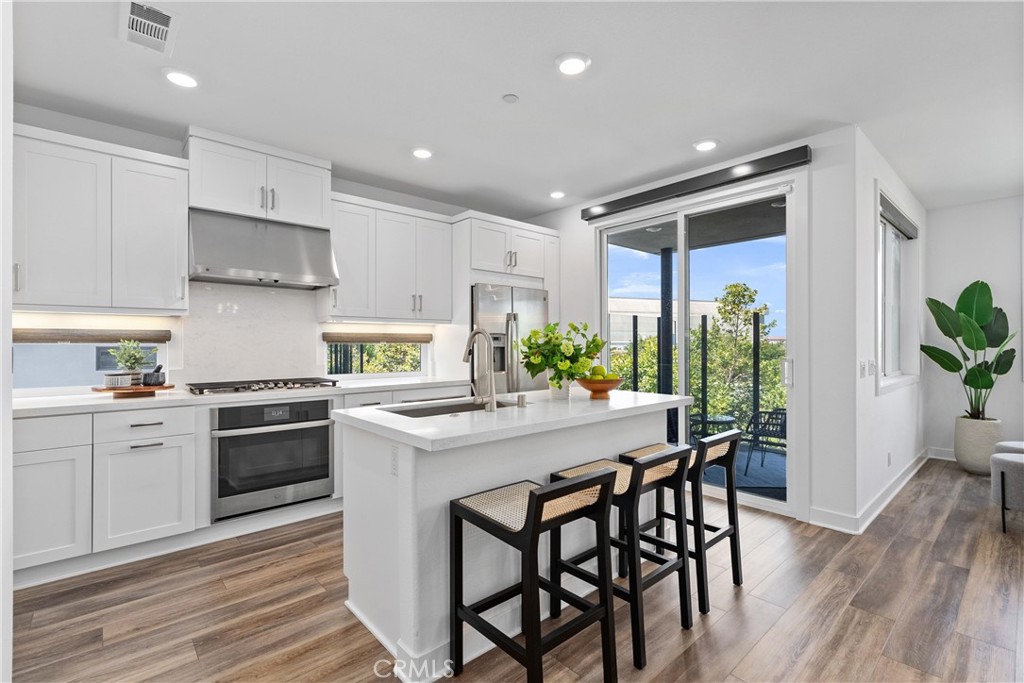 303 Lodestar Tustin, CA 92782 - Photo 7 of 37 a kitchen with stainless steel appliances granite countertop white cabinets stove a sink and dishwasher